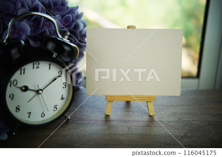 Empty card space for text message with wooden easel and alarm clcok on wooden background Empty card space for text message with wooden easel and alarm clcok on wooden background 116045175