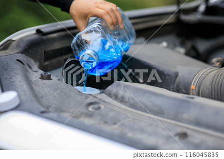 Pouring special cleaning solution bottle into a car window washer tank Pouring special cleaning solution bottle into a car window washer tank 116045835