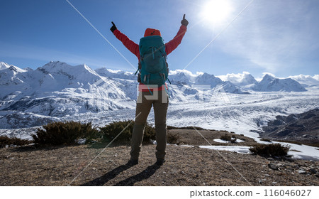 Woman hiker enjoy the view on mountain top cliff edge face to glacier mountains 116046027