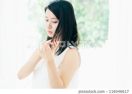 A young woman who is concerned about damaged hair A young woman who is concerned about damaged hair 116046617