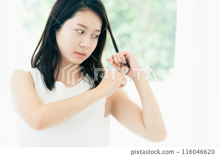 A young woman who is concerned about damaged hair A young woman who is concerned about damaged hair 116046620