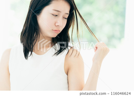 A young woman who is concerned about damaged hair A young woman who is concerned about damaged hair 116046624
