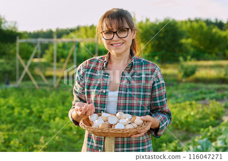 Woman with eggshell in wicker bowl, outdoor garden background Woman with eggshell in wicker bowl, outdoor garden background 116047271