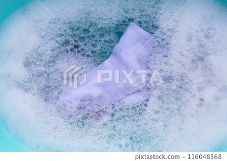 Dirty white socks soaked in water, dissolving detergent in blue basin. Dirty white socks soaked in water, dissolving detergent in blue basin. 116048568