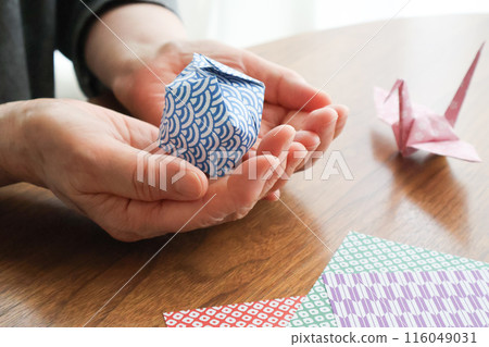 一位老婦人的手拿著摺紙製成的氣球 116049031