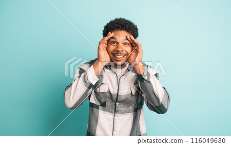 Stunned young man smiling at camera in blue studio 116049680