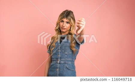 Dissatisfied transgender woman looking at camera and showing thumbs down Dissatisfied transgender woman looking at camera and showing thumbs down 116049718