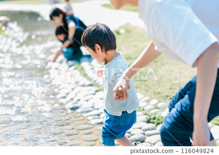 A boy playing with his father in a stream in the park 116049824