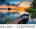 This image shows a serene lake at sunset with a wooden boat docked by a rustic pier, by Generative AI 116050049