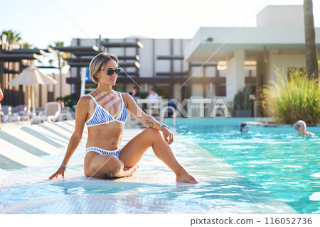 A girl sits near the pool after spa treatments. Turkey, hotel, vacation, travel, girl in a swimsuit 116052736