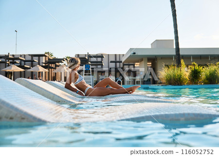 A girl sits near the pool after spa treatments. Turkey, hotel, vacation, travel, girl in a swimsuit A girl sits near the pool after spa treatments. Turkey, hotel, vacation, travel, girl in a swimsuit 116052752