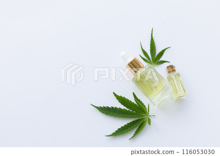 Two small bottles with cannabis oil and fresh cannabis leaves. Top view, copy space. 116053030