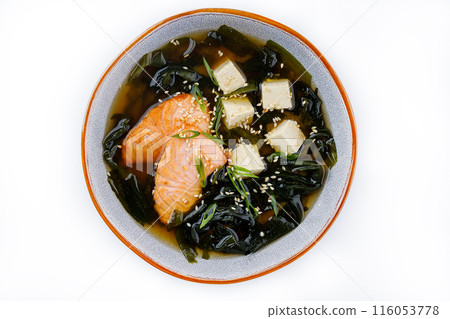 Japanese miso soup with salmon, tofu and seaweed in a bowl on a dark background. Top view. 116053778