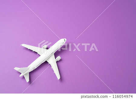 A figurine of a white airplane on a purple background. Commercial flights 116054974