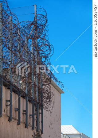 Barbed wire atop a prison wall 116055457
