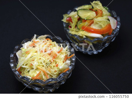Vegetable salad in a glass salad bowl on a black background. A portion of vegetable salad. Vegetable salad in a glass salad bowl on a black background. A portion of vegetable salad. 116055750