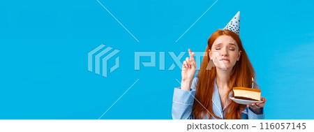 Eager and hopeful redhead european girl in nightwear, close eyes and cross fingers good luck, biting lip tempting or exciting, making wish hold birthday cake with lit candle, wear b-day cap Eager and hopeful redhead european girl in nightwear, close eyes and cross fingers good luck, biting lip tempting or exciting, making wish hold birthday cake with lit candle, wear b-day cap 116057145