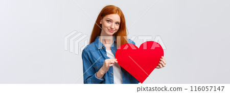 Lovely and shy, cute redhead teenage girl confess sympathy, give present on valentines day, handmade red heart, smiling silly and tender camera, express love and feelings, standing white background 116057147