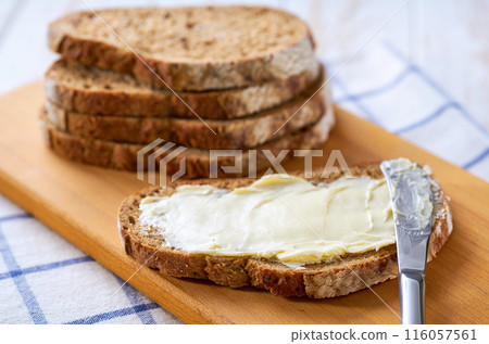 Tasty cut multigrain sourdough bread with fresh butter on a white wooden table. 116057561