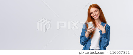 Oh so cute. Touched and pleased alluring redhead girlfriend receive love emoji, lovely message, texting, chatting boyfriend, holding smartphone, touch chest and smiling mobile display 116057831