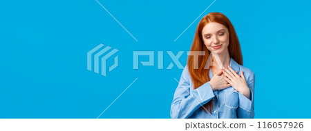 Tenderness, lifestyle and beauty concept. Cute, lovely redhead female in fancy nightwear, close eyes tilt head, touching heart as remember heartwarming moment, telling about dreams, blue background Tenderness, lifestyle and beauty concept. Cute, lovely redhead female in fancy nightwear, close eyes tilt head, touching heart as remember heartwarming moment, telling about dreams, blue background 116057926