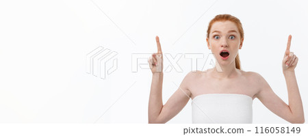 Portrait of young redhead female with perfect freckled skin showing something interesting at copy space wall for your advertising content. 116058149
