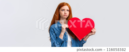 Unhapy brokenhearted cute redhead girl, sulking and looking up uneasy, distressed holding big red valentines day heart, was rejected, showed her feelings standing white background Unhapy brokenhearted cute redhead girl, sulking and looking up uneasy, distressed holding big red valentines day heart, was rejected, showed her feelings standing white background 116058382