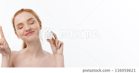 portrait of beautiful woman smiling while taking some facial cream isolated on white background with copy space. portrait of beautiful woman smiling while taking some facial cream isolated on white background with copy space. 116058621