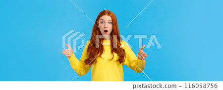Woman impressed with enourmous size of present. Wondered and amused good-looking redhead girl in yellow winter sweater, shaping big object, showing length or distance with stretched hands 116058756