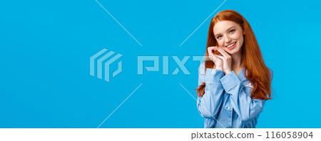 Tenderness, beauty and lifestyle concept. Cute happy charming redhead woman in lovely nightwear, getting ready sleep, wearing pyjama, tilting head and touching face, smiling, blue background 116058904