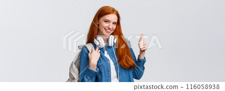 Girl found excellent part-time job after university classes. Attractive redhead woman with backpack, headphones over neck, showing thumb-up and smiling in approval, recommending 116058938