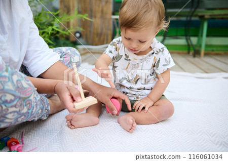 Mother and child playing with wooden toys outdoors Mother and child playing with wooden toys outdoors 116061034