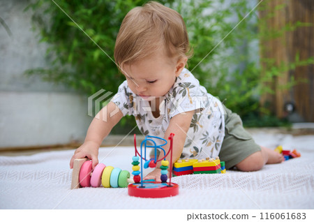 Curious baby playing with colorful toys on a mat Curious baby playing with colorful toys on a mat 116061683