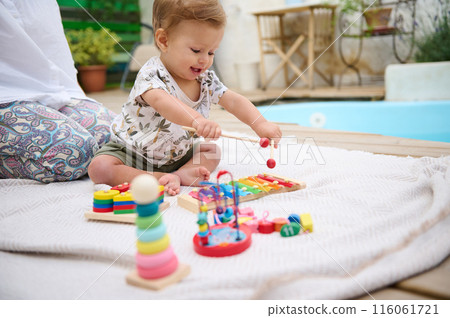 Happy baby playing with toys outdoors by the poolside Happy baby playing with toys outdoors by the poolside 116061721