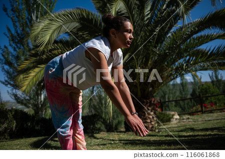 Woman doing yoga outdoors under palm tree in garden 116061868