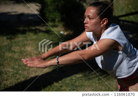 Woman practicing yoga outdoors in a sunny park 116061870