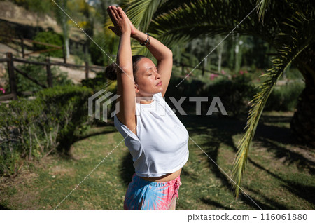 Woman practicing yoga outdoors under sunny sky in a park Woman practicing yoga outdoors under sunny sky in a park 116061880
