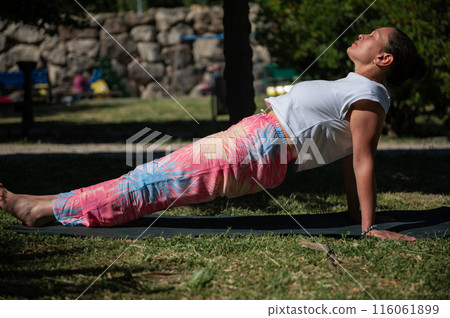 Woman practicing yoga outdoors on a sunny day in the park 116061899