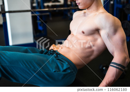 Bodybuilder doing abs workout on bench in gym. Bodybuilder doing abs workout on bench in gym. 116062180