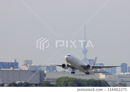 A passenger plane takes off and ascends from Haneda Airport. A JAL plane takes off with Tokyo Skytree in the background. 116062275