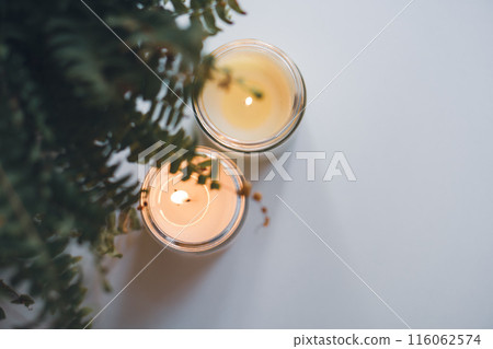 Creating a warm and cozy atmosphere with candles and fern leaves to enhance the interior decor 116062574