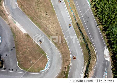 Motor vehicles racing around curve on race track 116062664