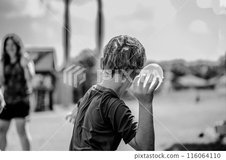 Young Caucasian boy taking aim to throw a water balloon.  116064110