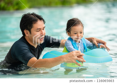 happy father with toddler baby girl playing in an inflatable ring in swimming pool happy father with toddler baby girl playing in an inflatable ring in swimming pool 116065663