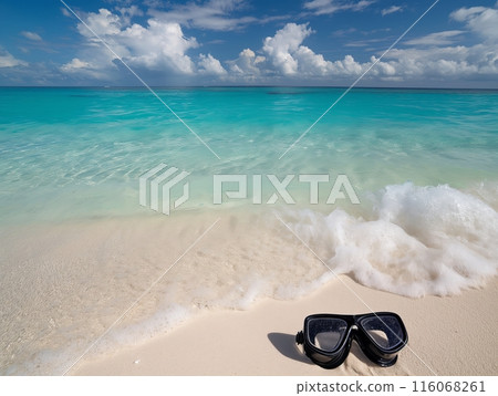 A black snorkel mask lies on a sandy beach with gentle waves and clear turquoise water under a partly cloudy sky. 116068261
