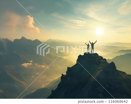 Two climbers stand triumphantly on a mountain peak at sunrise, overlooking a vast, misty valley. 116068642