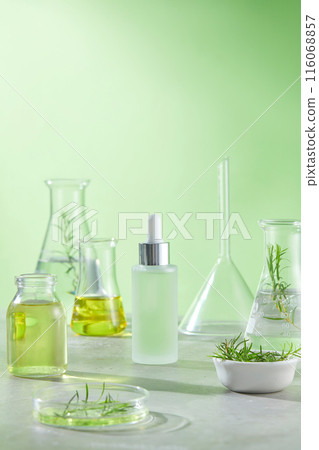 An unbranded serum bottle contains light green essence surrounded by many laboratory instruments, over the green color background. Copy space for adding text, front angle shot photo An unbranded serum bottle contains light green essence surrounded by many laboratory instruments, over the green color background. Copy space for adding text, front angle shot photo 116068857