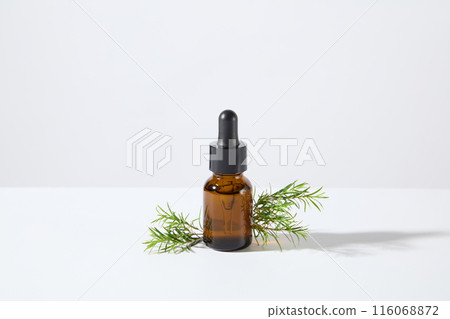 A brown serum bottle without label placed in the center of white background photo, with a few tea tree branches decorated on both sides. Blank space for designing and advertising A brown serum bottle without label placed in the center of white background photo, with a few tea tree branches decorated on both sides. Blank space for designing and advertising 116068872