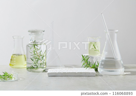Natural extract product advertising photo with empty showcase pedestal in the center, lab glassware displayed on both sides of it, contain transparent and yellow liquid. Frontal shot, copy space 116068893