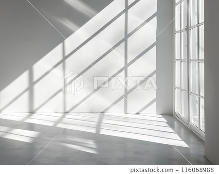 Sunlight streams through a grid-patterned window, casting geometric shadows on a white wall and floor, creating a minimalist and serene atmosphere. 116068988
